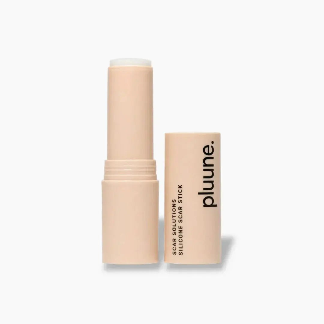 Pluune silicone scar stick standing open next to its cap on a light gray background